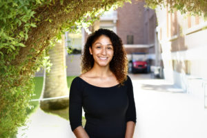 Student CEO Jaesa Strong, smiling in a long sleeved black shirt in front of a sunny building at the University of Arizona